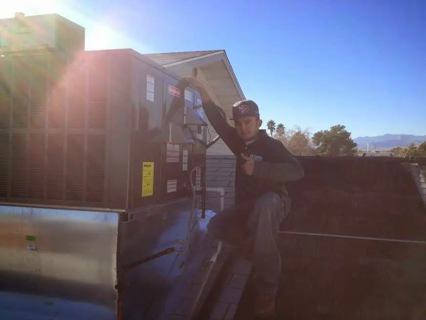 HVAC technician performing AC Tune-Up on a rooftop unit in Clemson University